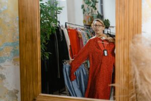 woman fitting red dress in front of mirror