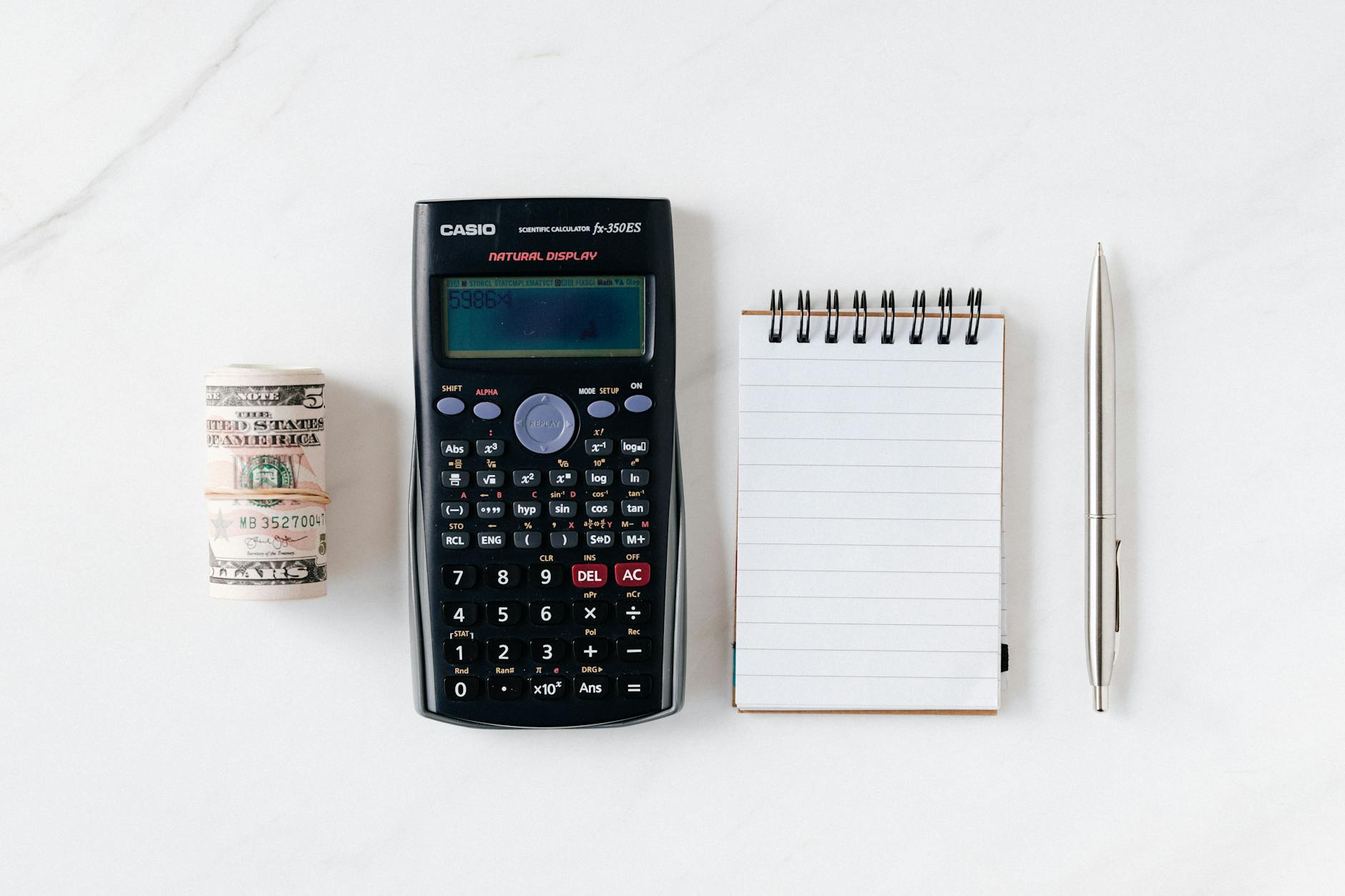 composition of calculator with paper money and notebook with pen