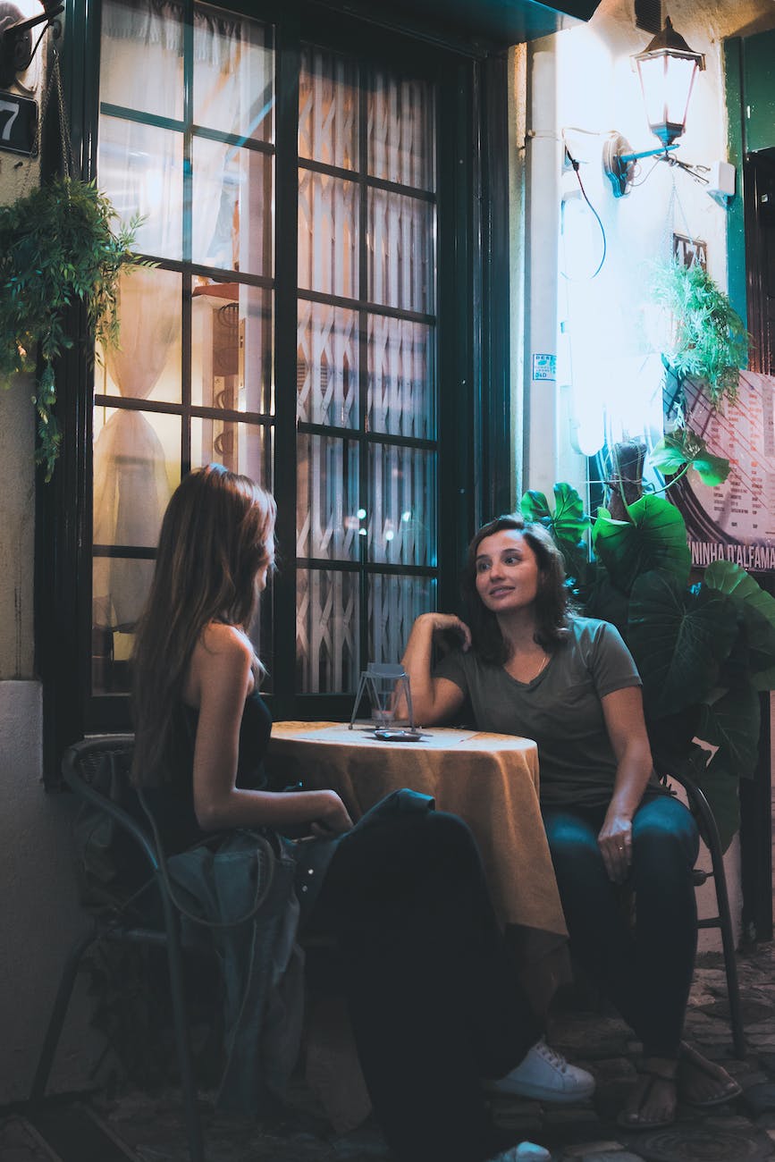 two women sitting and chatting near table